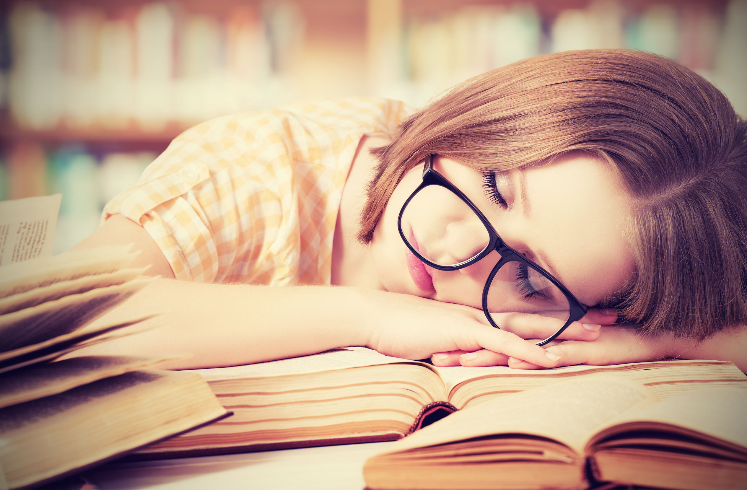 26519532 - tired student girl with glasses sleeping on the books in the library