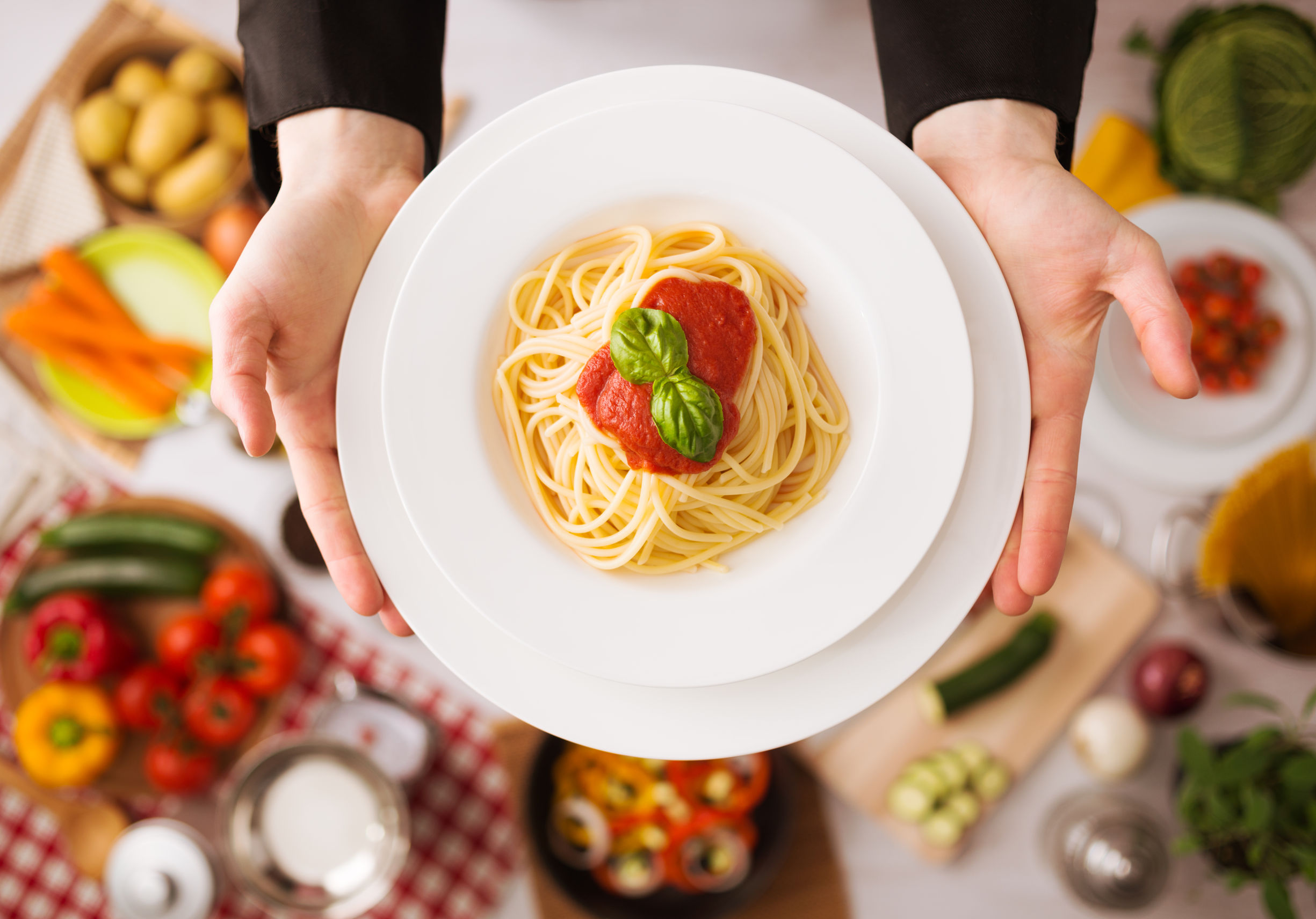 39375627 - professional chef's hands cooking pasta on a wooden worktop with vegetables, food ingredients and utensils, top view